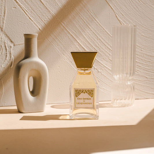 Das Flakon des exklusiven Nischenparfums Oud Saffron von der Marke Lesquendieu neben einem Tongefaess und einer Glasvase