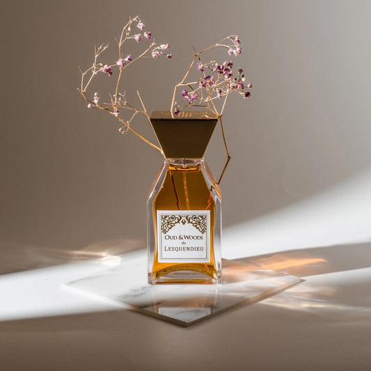 Das Flakon des exklusiven Nischenparfums Oud and Woods von der Marke Lesquendieu mit einem Blumenzweig