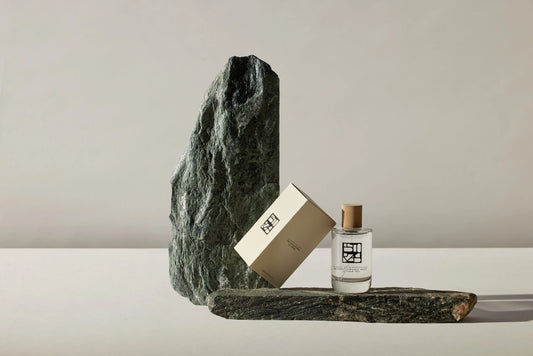 Ein edles Glasflakon mit einem Nischenduft der Marke Estoras auf einem Strin, angelehnt ist die Verpackung