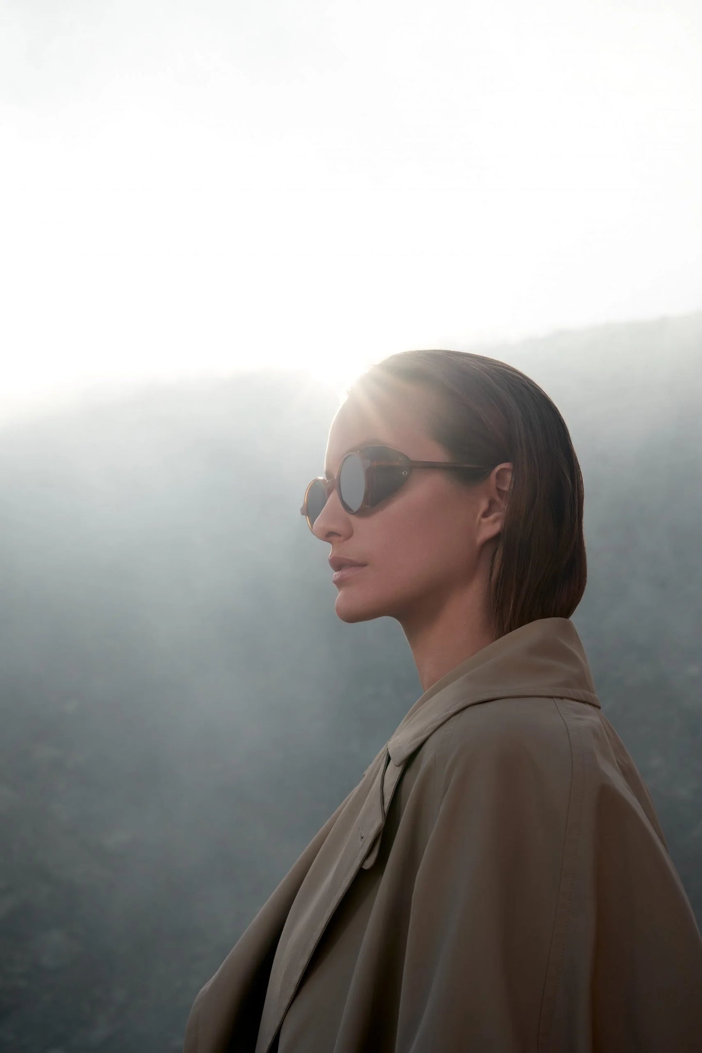 Eine Frau mit Fliegerbrille und Trenchcoat, als Gesicht von Estoras