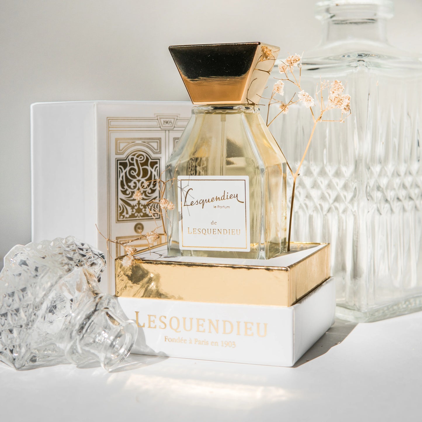Das Flakon des exklusiven Nischenparfums le lesquendieu von der Marke Lesquendieu auf einem goldenen Farnblatt neben einem Glas