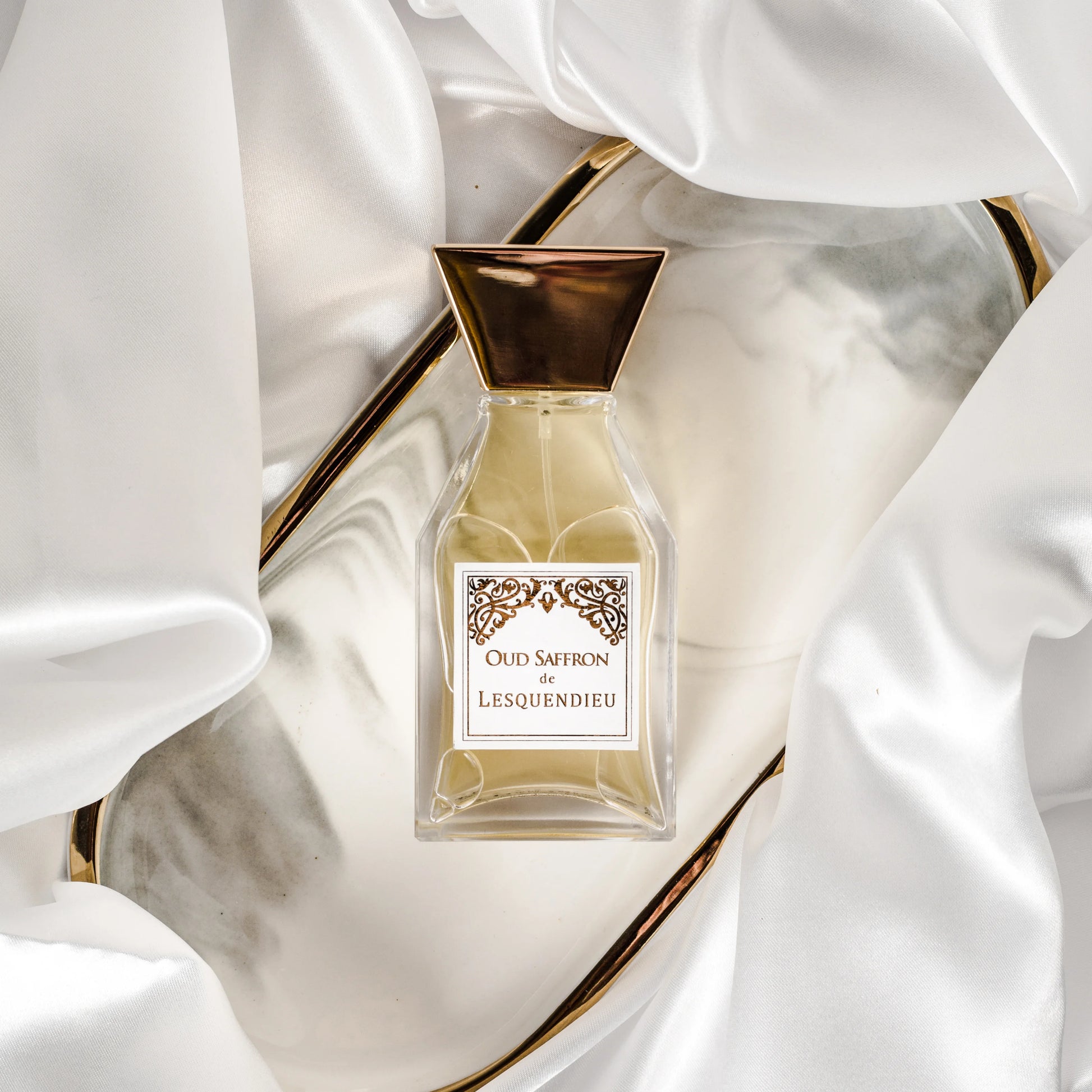 Das Flakon des exklusiven Nischenparfums Oud Saffron von der Marke Lesquendieu auf einer Glasschale in einem Seidentuch